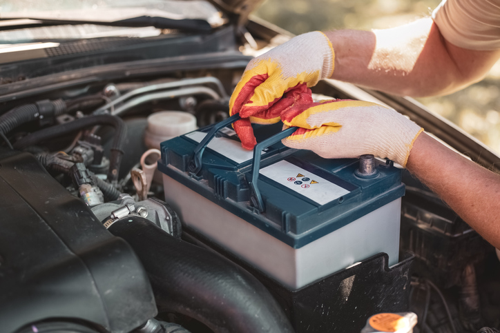 Mechanic lifting out a car battery.