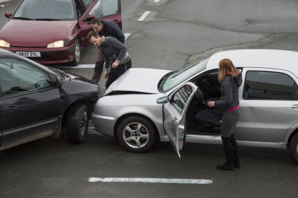 Two men looking at cars collision on road, woman standing near car. accident in Ontario